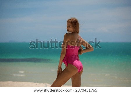 Beautiful girl in pink swimsuit posing on the beach at sunny day. High quality photo