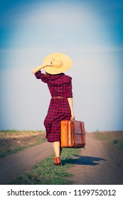 Beautiful girl in plaid dress with bag on countryside - Shutterstock ID 1199752012