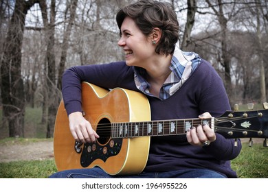 Beautiful girl playing guitar outdoors
