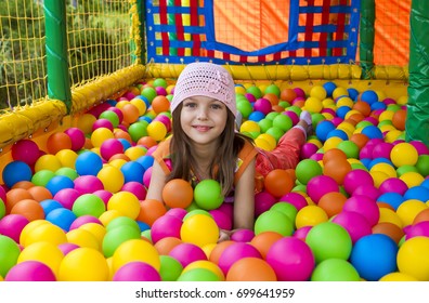 Beautiful girl is playing in plastic balls.
