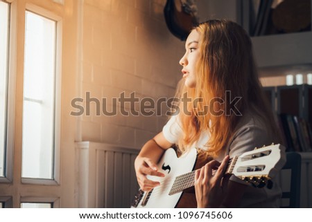 Beautiful girl playing the white guitar in the room near window, soft and blur concept.