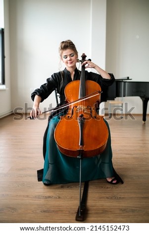 a beautiful girl plays the cello in the classroom, the cello plays with a bow