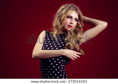 Beautiful girl in a polka-dot dress studio red background