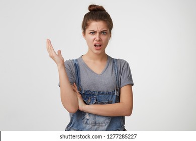 Beautiful girl portrays indignation, discontent, indignation one arm raised,one crossed isolated on white background.Someone said a terrible nonsense.