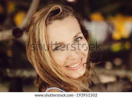 Similar – Young blonde woman portrait laughing outdoors sitting in a garden, and looking at camera.