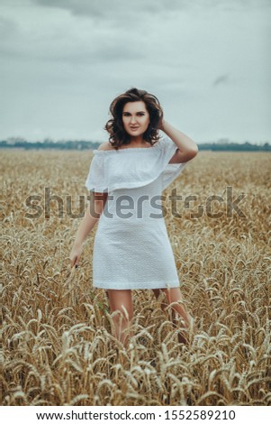 Beautiful girl posing in a field with golden ears of wheat
