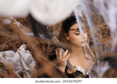 Beautiful Girl Posing in Halloween Photo Zone with Spider Web in Foreground, Bright Makeup, Black Outfit, and Large Headpiece