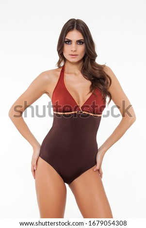 beautiful girl is posing in a stylish designed chic brown swimsuit on white background.