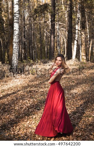 beautiful girl in a red dress in the autumn forest