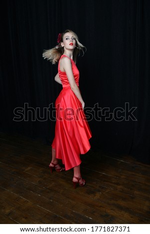beautiful girl in a red evening dress posing on a black background