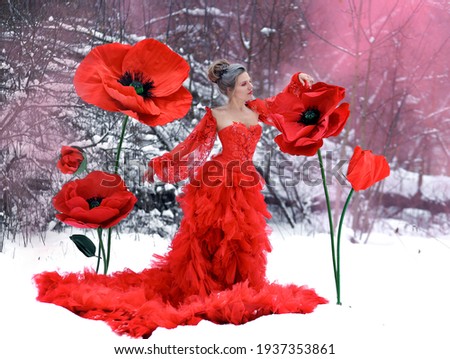 Beautiful girl in red evening gown on poppy flowers in winter