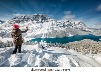 Beautiful girl with red hat taking picture with smartphone near Peyto Lake, Banff, Canada.