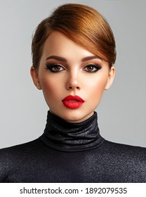 Beautiful girl with red lips and short hair. Pretty face of an young sensual woman. Closeup portrait of a model with bright makeup on a face. Attractive female posing at studio  in black closes.    
