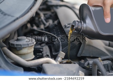 beautiful girl Refueling and pouring oil quality into the engine motor car Transmission and Maintenance Gear .Energy fuel concept. car maintenance