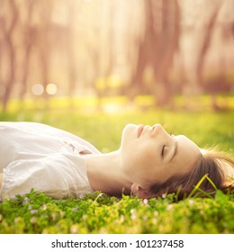 Beautiful Girl Relaxing Lying On The Grass In The Garden