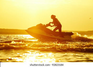 Beautiful Girl Riding Her Jet Skis In The Sea At Sunset . Spray