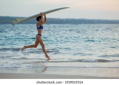 beautiful girl runs along the beach with a surfboard. high quality photo - Powered by Shutterstock