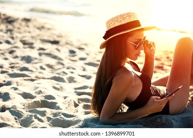 Beautiful girl sends a message with her smartphone at the beach.