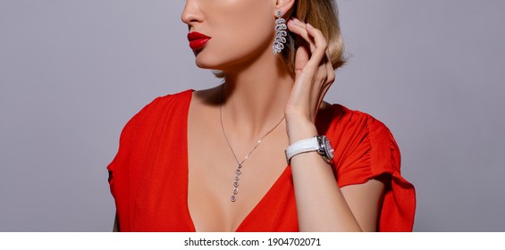 Beautiful girl with set jewelry. Fashion model girl posing in the studio is wearing elegant clothes, exquisite jewelry on gray background. attractive girl measures luxury earrings                  
