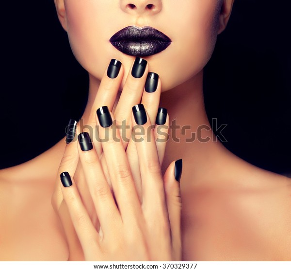 Beautiful girl showing black manicure nails .\
makeup and cosmetics