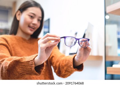 Beautiful Girl Showing A Glasses In Optician Store, Asian Girl In Sweater Chooses Glasses, Selective Focus