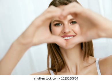 Beautiful Girl Showing Heart With Hands. Portrait Of Young Smiling Woman With Natural Face Makeup, White Smile And Fresh Clean Facial Skin Making Heart Shape With Hands. Love Concept. High Quality - Shutterstock ID 1025160934