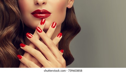 Beautiful girl showing red  manicure nails . makeup and cosmetics. Brunette  girl with long  and   shiny curly hair