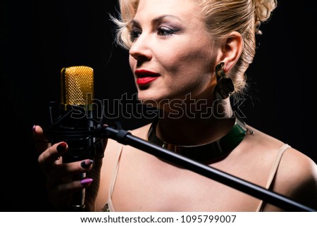 beautiful girl sings into a microphone on black background