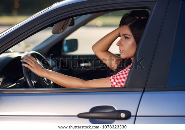 A beautiful girl sits inside a blue car, makes a\
make-up and looks in the mirror while driving. Danger on the road,\
irresponsible driving.