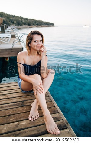 Beautiful girl sitting on a wooden pier by the sea