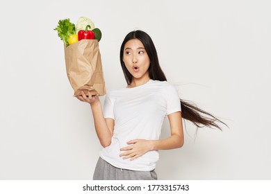 A Beautiful Girl With A Slim Figure Is Holding A Packet Of Vegetables 