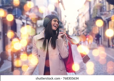 A Beautiful Girl Smiles And Is Happy While Shopping In The Stores With Sales At Christmas, Around The City. Concept Of: Shopping, Holidays, Happiness, Christmas.