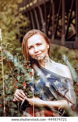 Beautiful girl smiling in nature, among the berries and herbs in a T-shirt with the American flag.