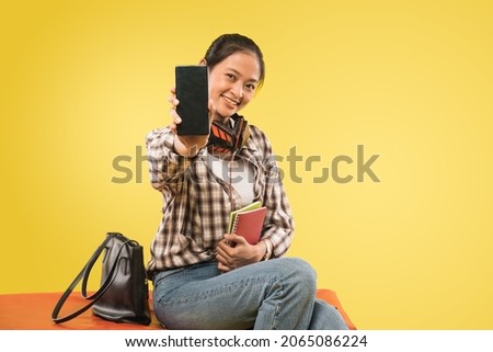 beautiful girl smiling showing camera phone screen while sitting