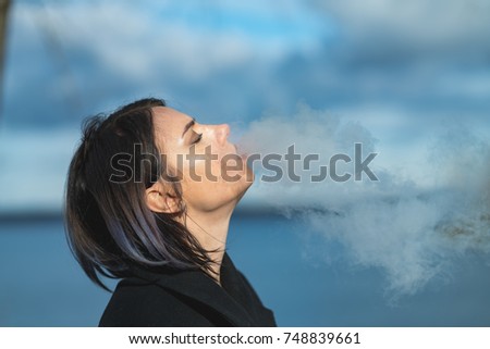 beautiful girl smokes an e-cigarette