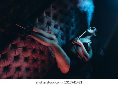 Beautiful Girl smoking hookah in Nightclub. Exhaling smoke. Sexy girl smokes hookah