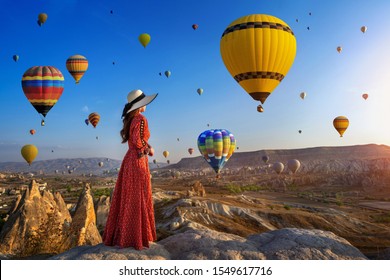 Beautiful girl standing and looking to hot air balloons in Cappadocia, Turkey.