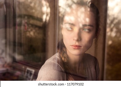 Beautiful girl standing at the window watching