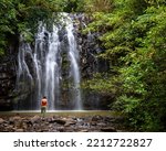 beautiful girl stands under fabulous tropical waterfall in australian rainforest, vacation in northern queensland, australia, atherton tablelands