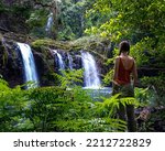beautiful girl stands under fabulous tropical waterfall in australian rainforest, vacation in northern queensland, australia, atherton tablelands