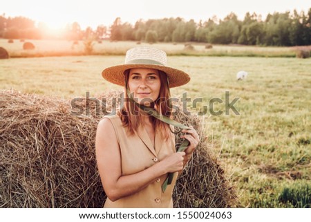 Beautiful girl in straw hat in a field, haystack