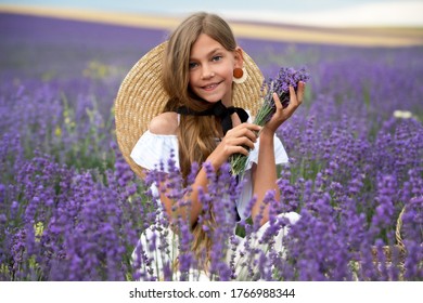 Beautiful girl  in straw hat on the lavender field on sunset. Girl collect lavender.