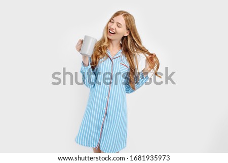 Beautiful girl in striped pajamas, with a Cup in her hands , drinking coffee or tea in the early morning, on a white background