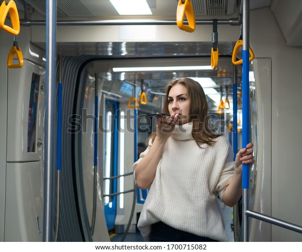 Beautiful\
girl in subway car records voice message. Woman passenger solves\
business issues while in subway car. City\
life.