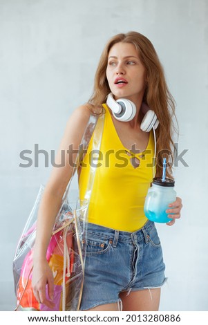 Beautiful girl in summer outfit with big headphones and glass of cold beverage. Summertime lifestyle