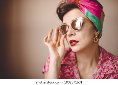 A beautiful girl in sunglasses and a bright headscarf. Retro style, in cool colors.