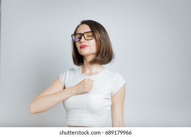 Beautiful girl swears or promises wearing glasses, isolated on gray background