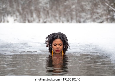 Beautiful girl swimming in the cold water of a lake or river, cold therapy, ice swim with winter landscape and forest on background