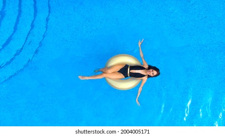 Beautiful Girl Swims In The Pool On An Inflatable Ring. Aerial. Top View From Drone.