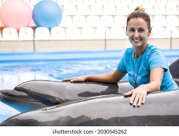 The beautiful girl the trainer with a smile near dolphins. Concept love of the person to marine animals. Harmony in the nature. Careful attitude to animals - Shutterstock ID 2030545262